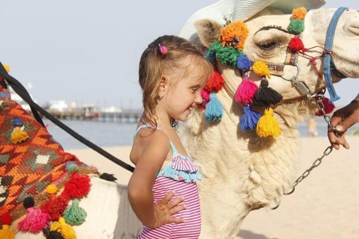 deklica, ki stoji poleg konja na plaži