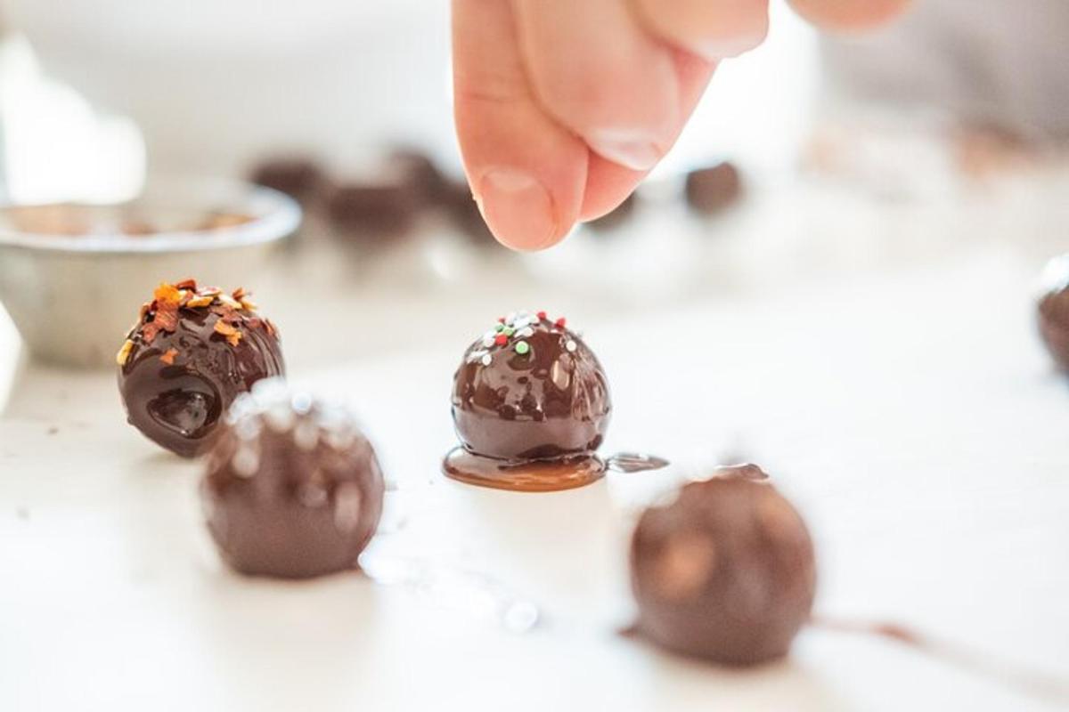 a person picking up a chocolate ball from a table