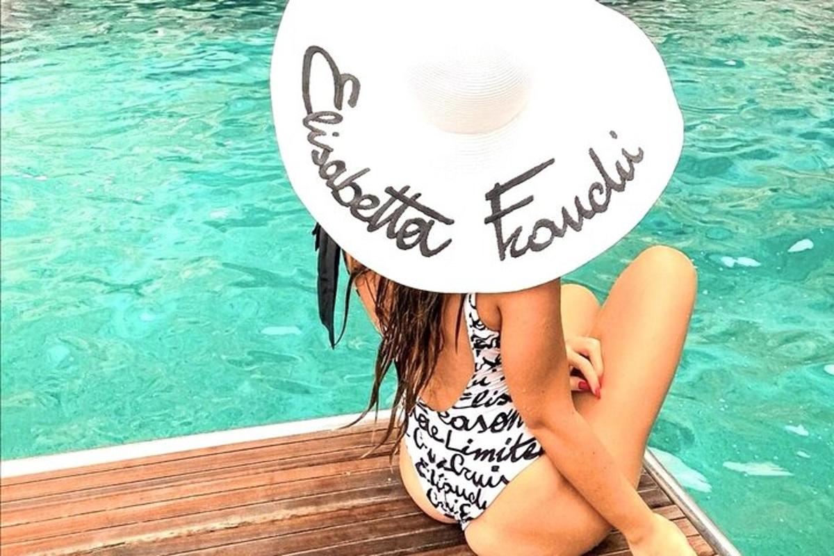 uma garota sentada em um cais ao lado de uma piscina
