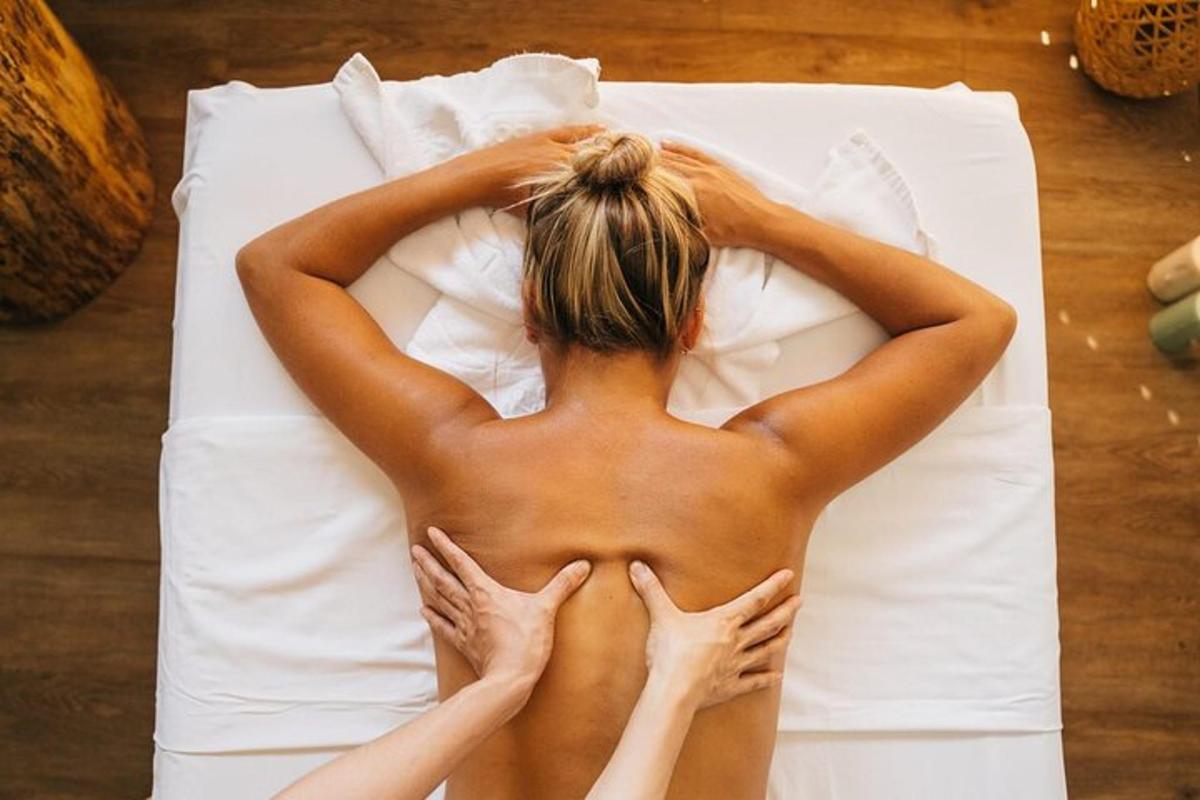 una donna a torso nudo sdraiata su un letto con le mani sulla schiena