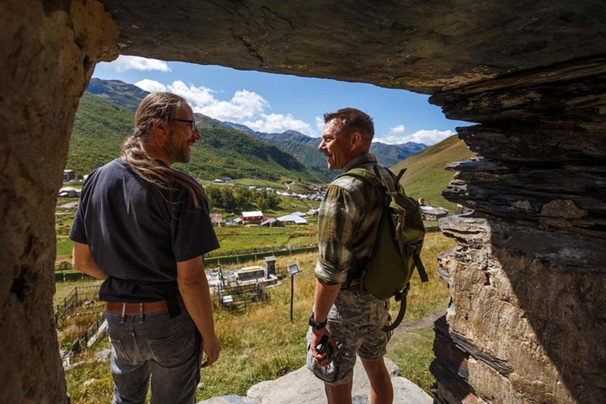 two men standing in a cave looking out of a window