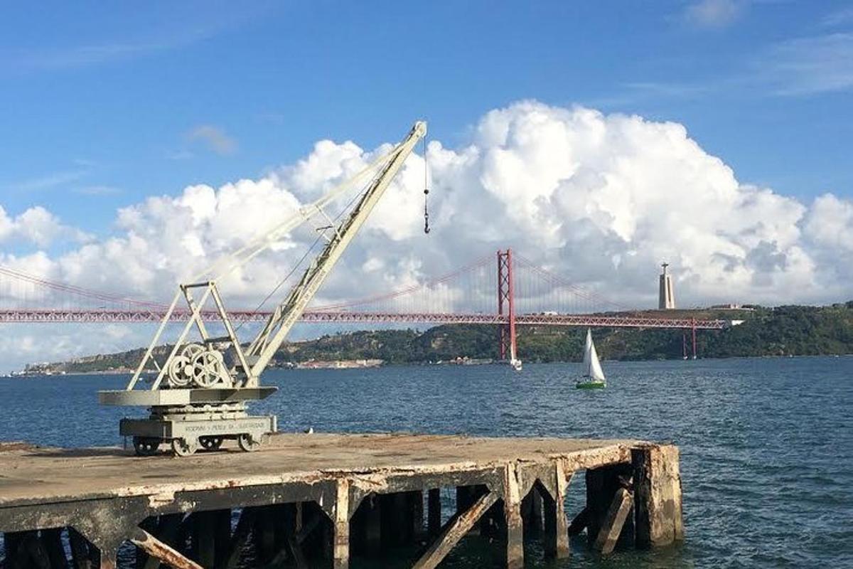 una grua en un moll amb un pont al fons