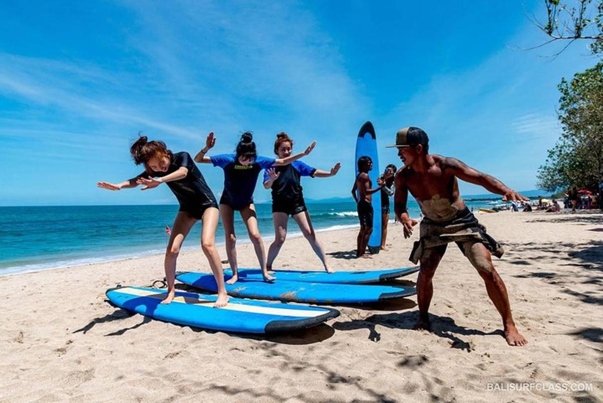 Un grupo de personas de pie sobre tablas de surf en la playa.