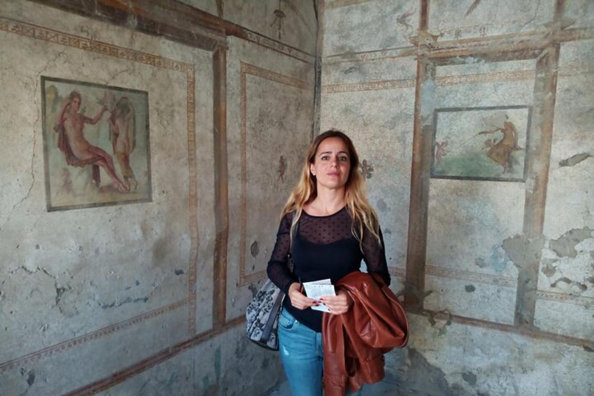 Una mujer parada en una habitación con pinturas en las paredes.