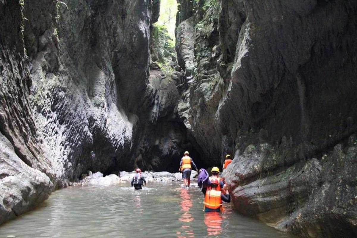 un gruppo di persone che camminano attraverso un fiume in un canyon