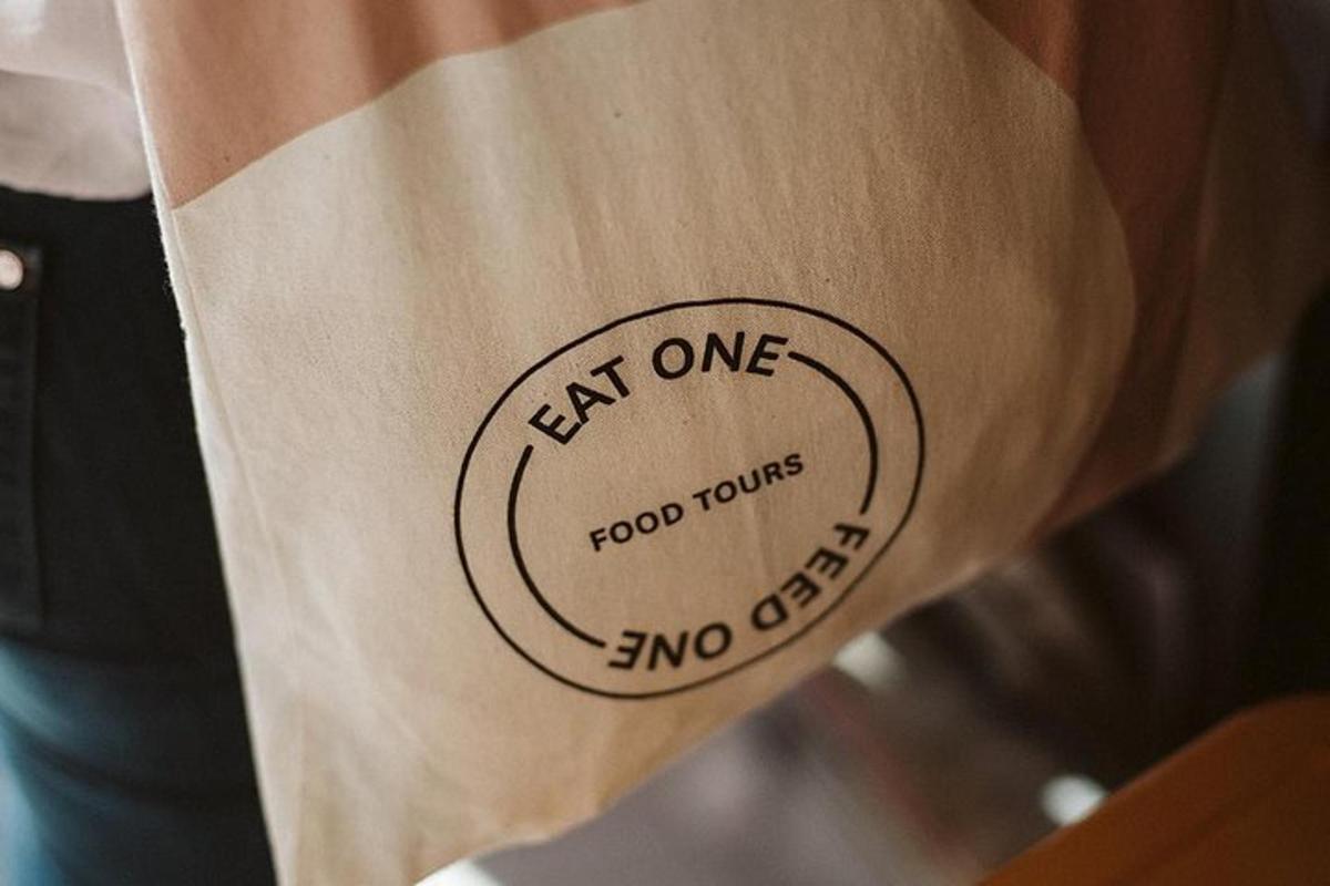 oseba z napisom aeat one food tour na papirnati vrečki