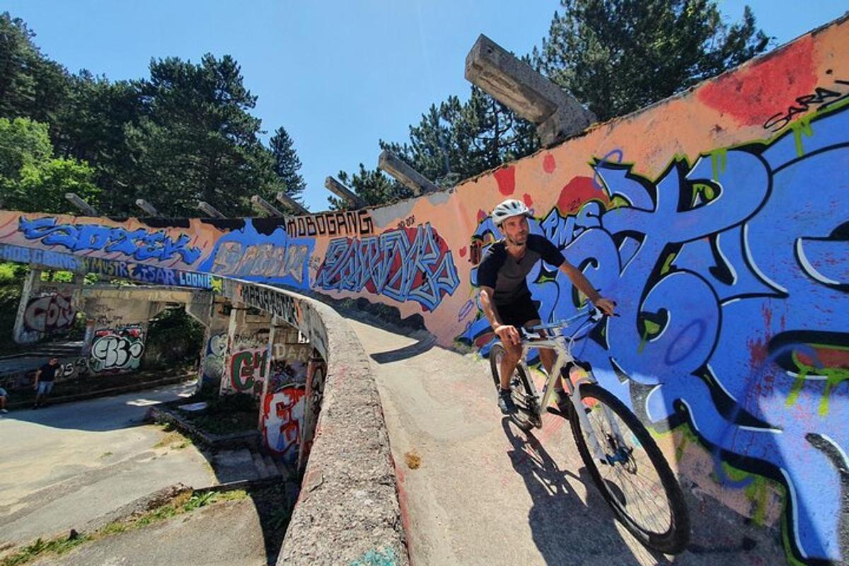 un bărbat mergând cu bicicleta pe un pod acoperit de graffiti