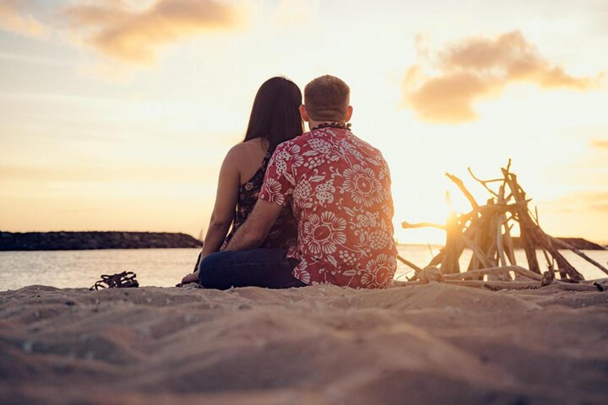 en mann og en kvinne som sitter på stranden og ser på solnedgangen