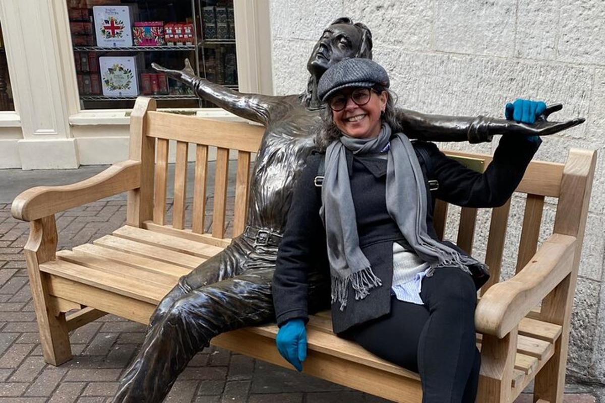 una donna seduta su una panchina accanto a una statua