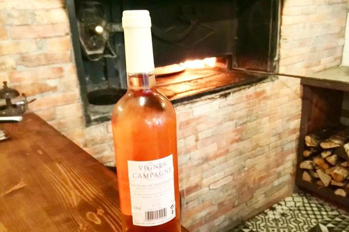 Una botella de vino sobre una mesa frente a un horno.