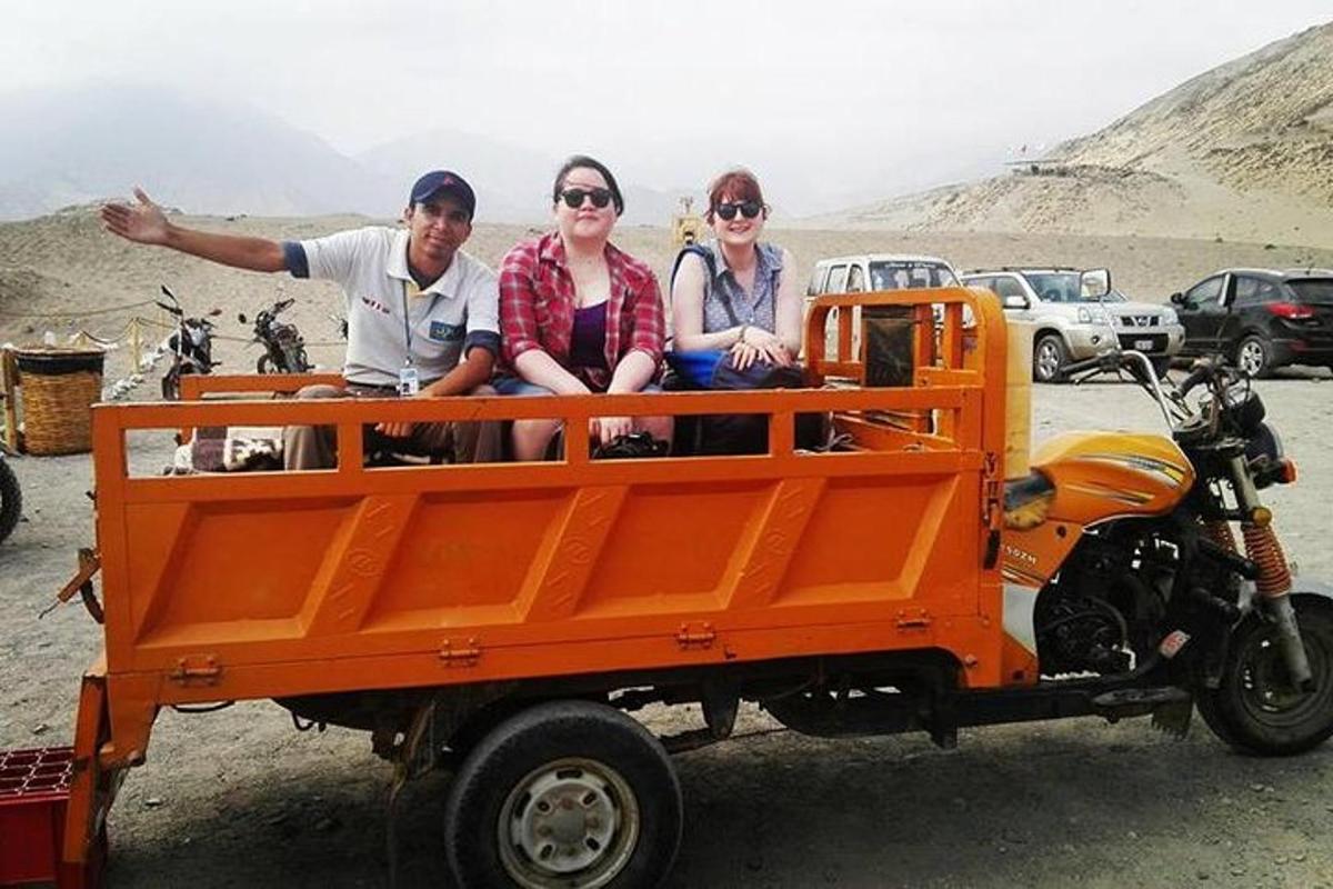 tiga orang duduk di belakang trak oren