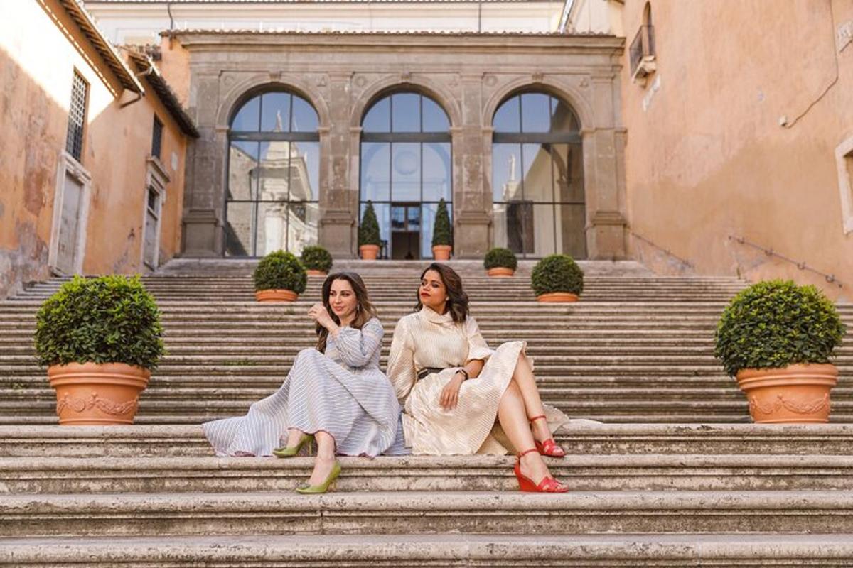 two women sitting on the stairs in front of a building
