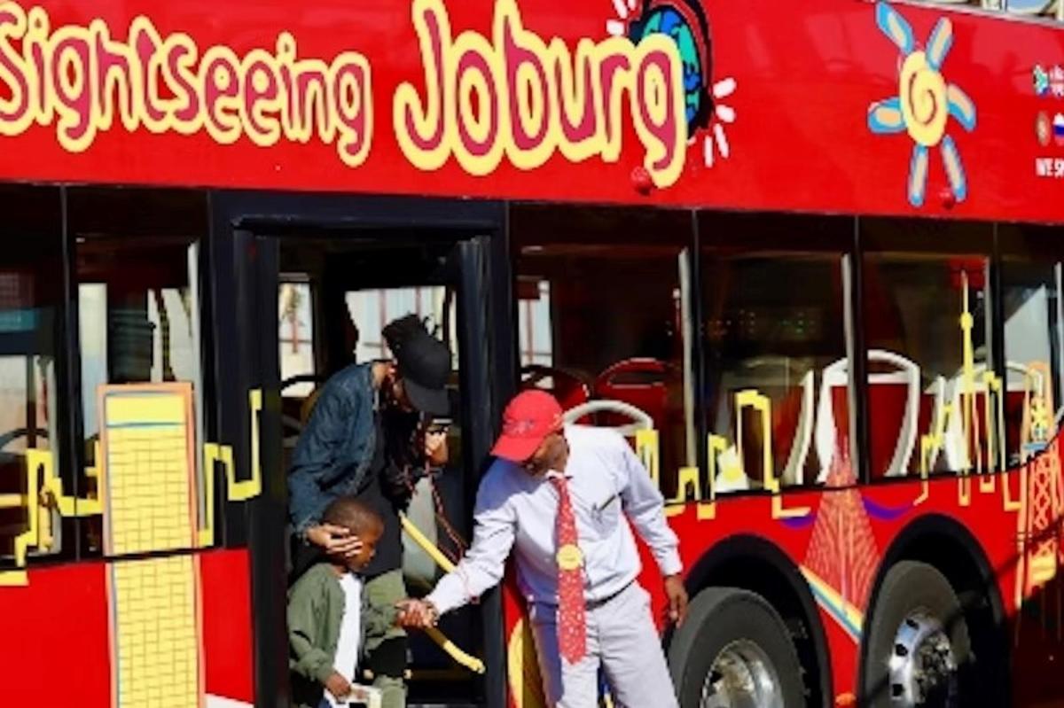 skupina lidí vycházejících z červeného autobusu
