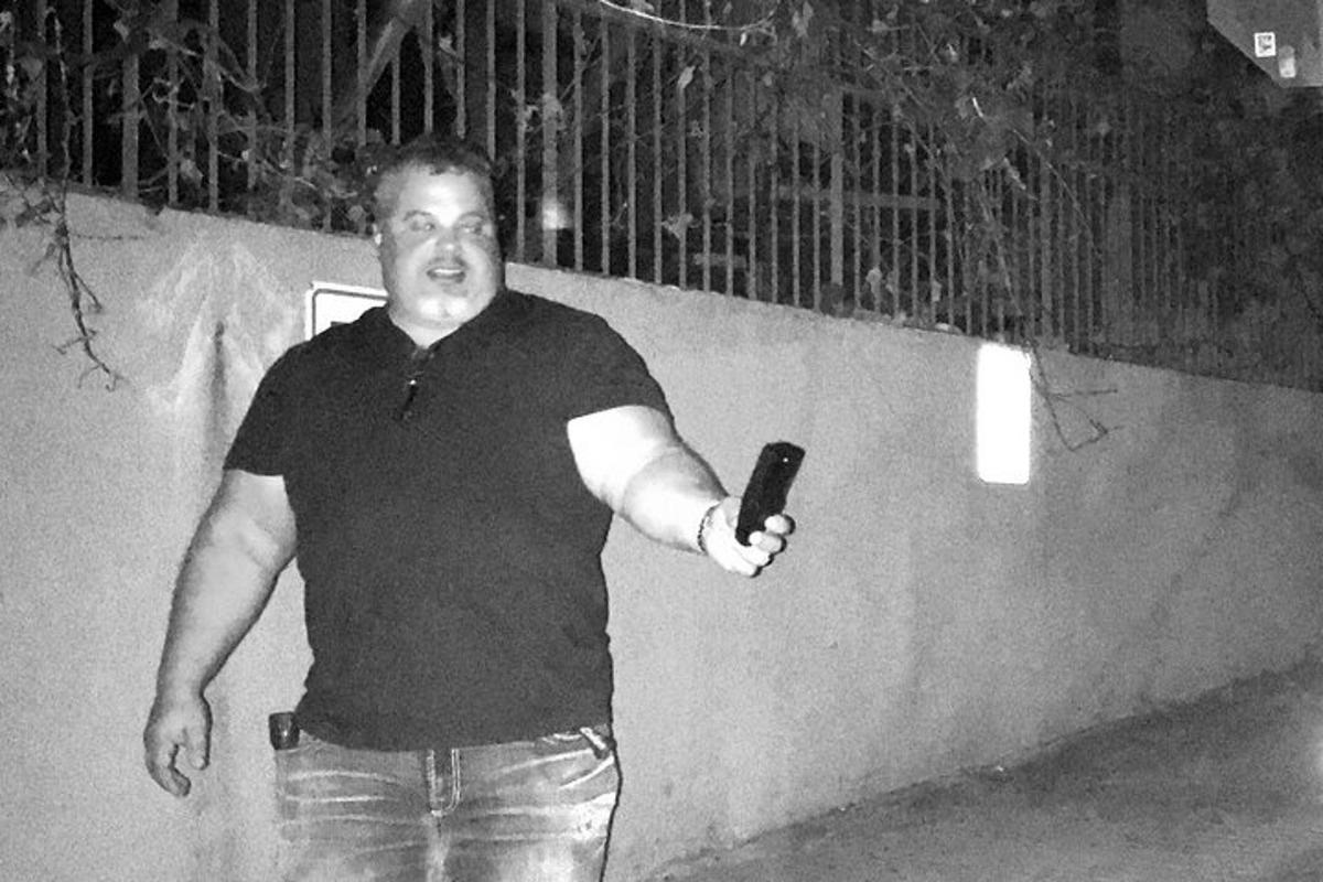 muž stojící u zdi a držící dálkové ovládání