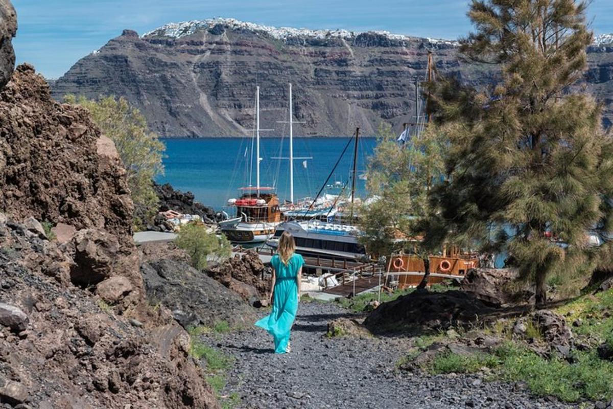 una donna in un vestito blu che cammina sulle rocce vicino a un porto turistico
