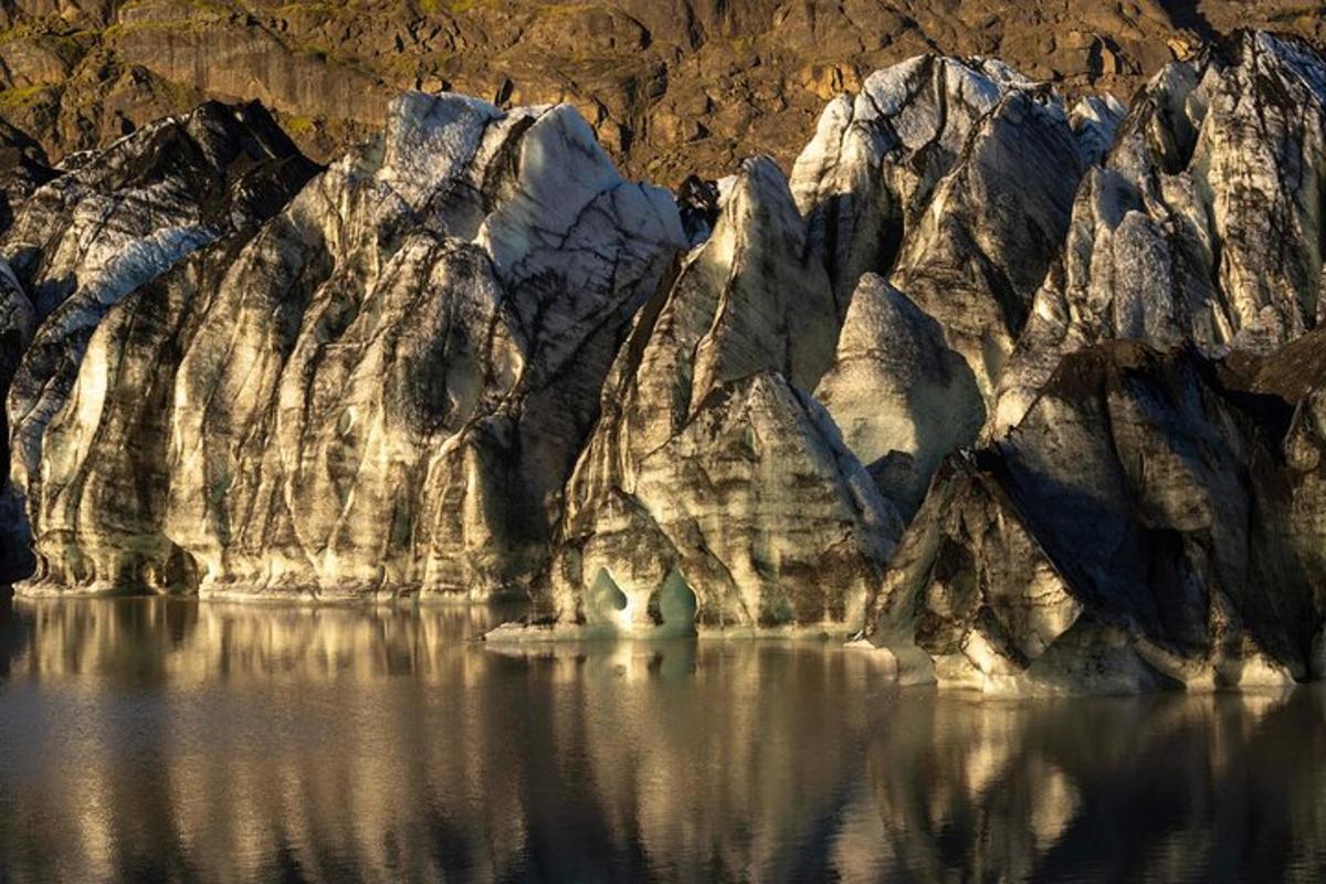 Una gran pared de roca con agua delante.