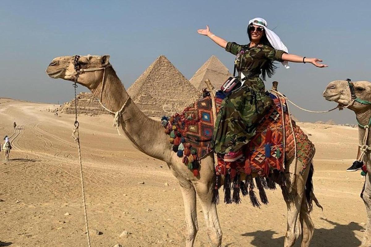 a woman riding on a camel in front of the pyramids