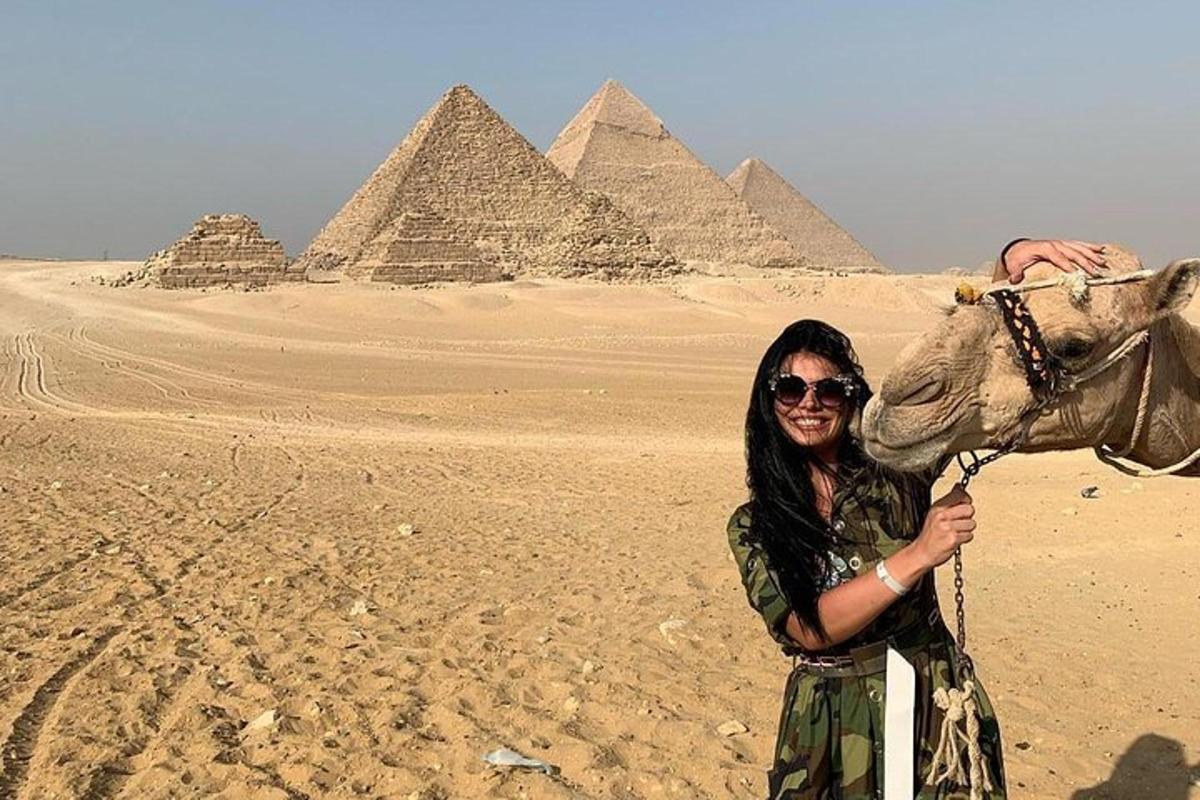 a woman with a camel in front of pyramids