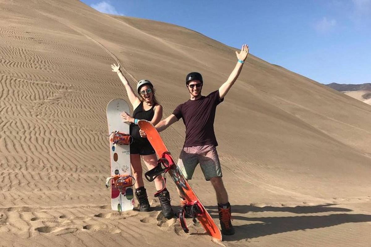 un uomo e una donna in piedi nel deserto con i loro snowboard