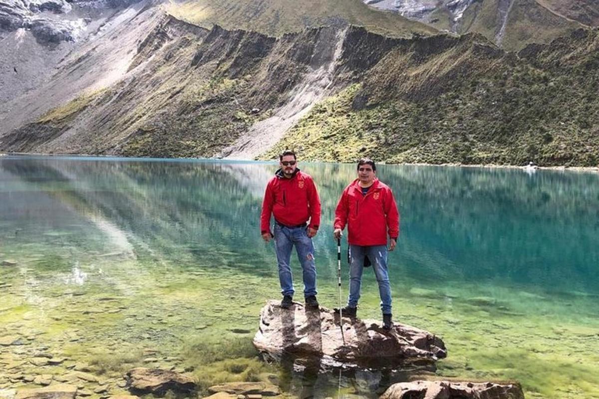 Dos personas de pie sobre una roca en un cuerpo de agua.