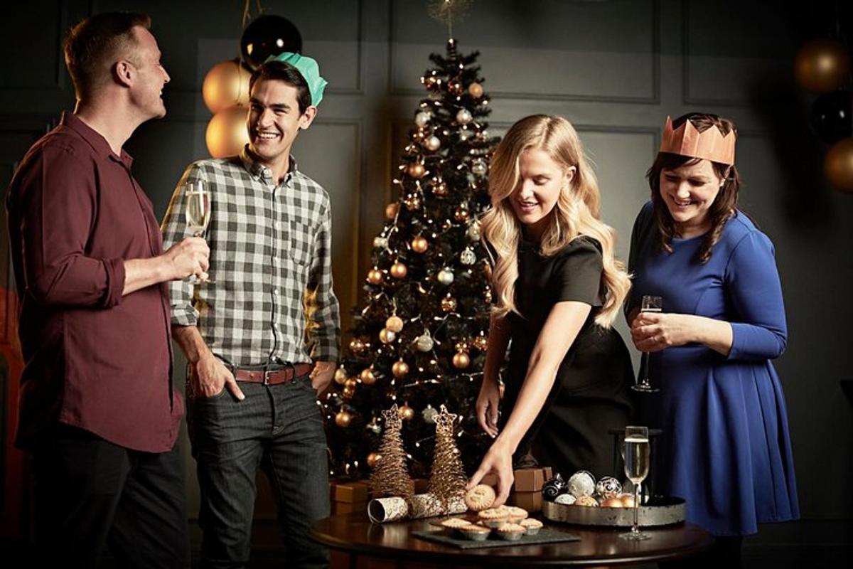 Un grupo de personas de pie alrededor de un árbol de Navidad.