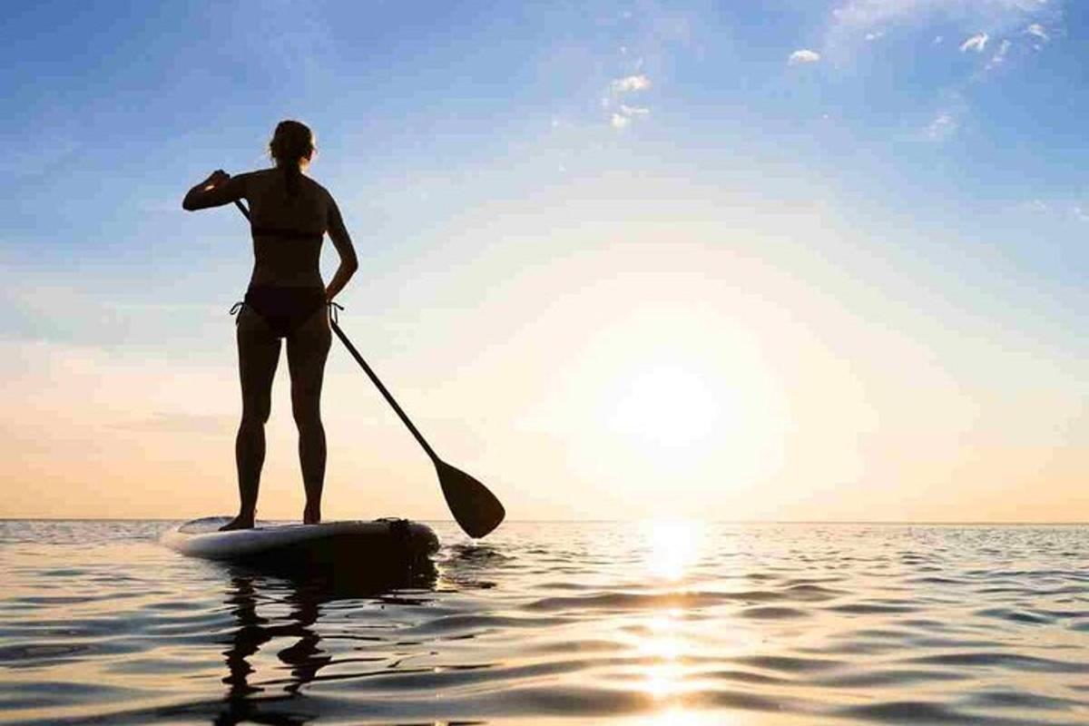 Žena stojí na paddleboardu ve vodě