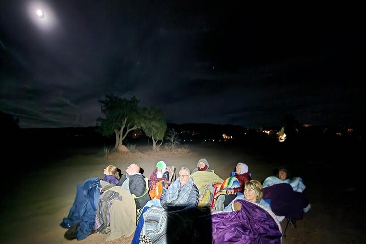 a group of people sitting on the beach at night