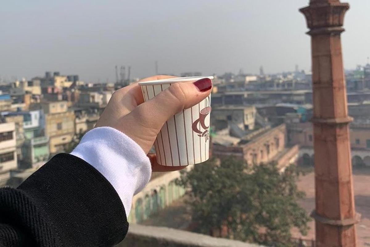 a person holding a cup of coffee in front of a city
