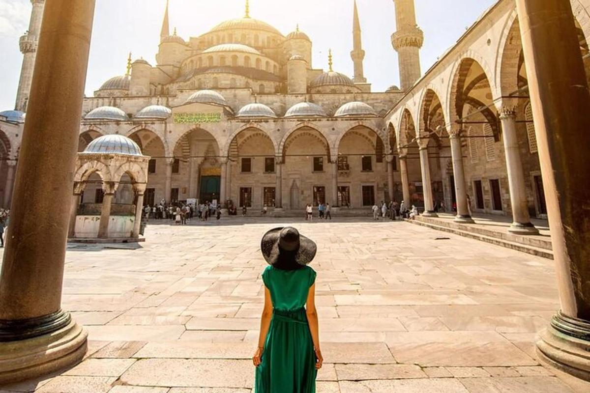 une femme en robe verte debout devant une mosquée