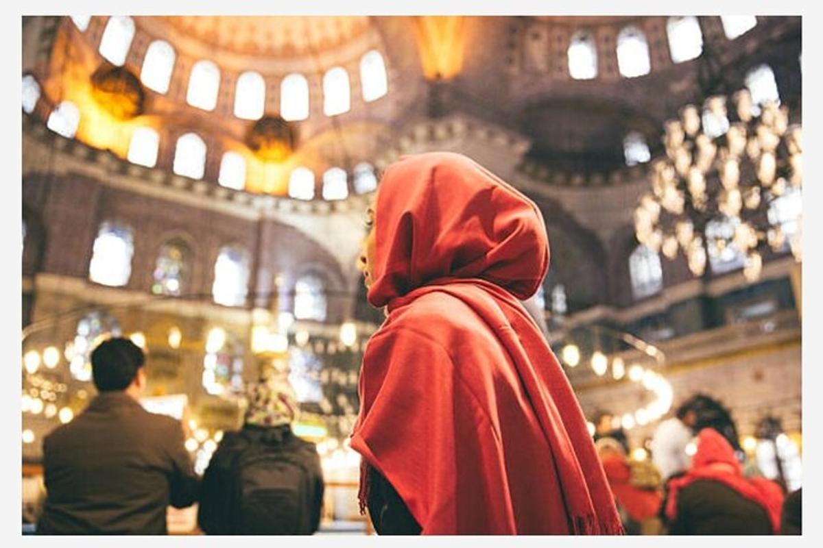 une personne portant un hijab rouge debout à l'intérieur d'une mosquée
