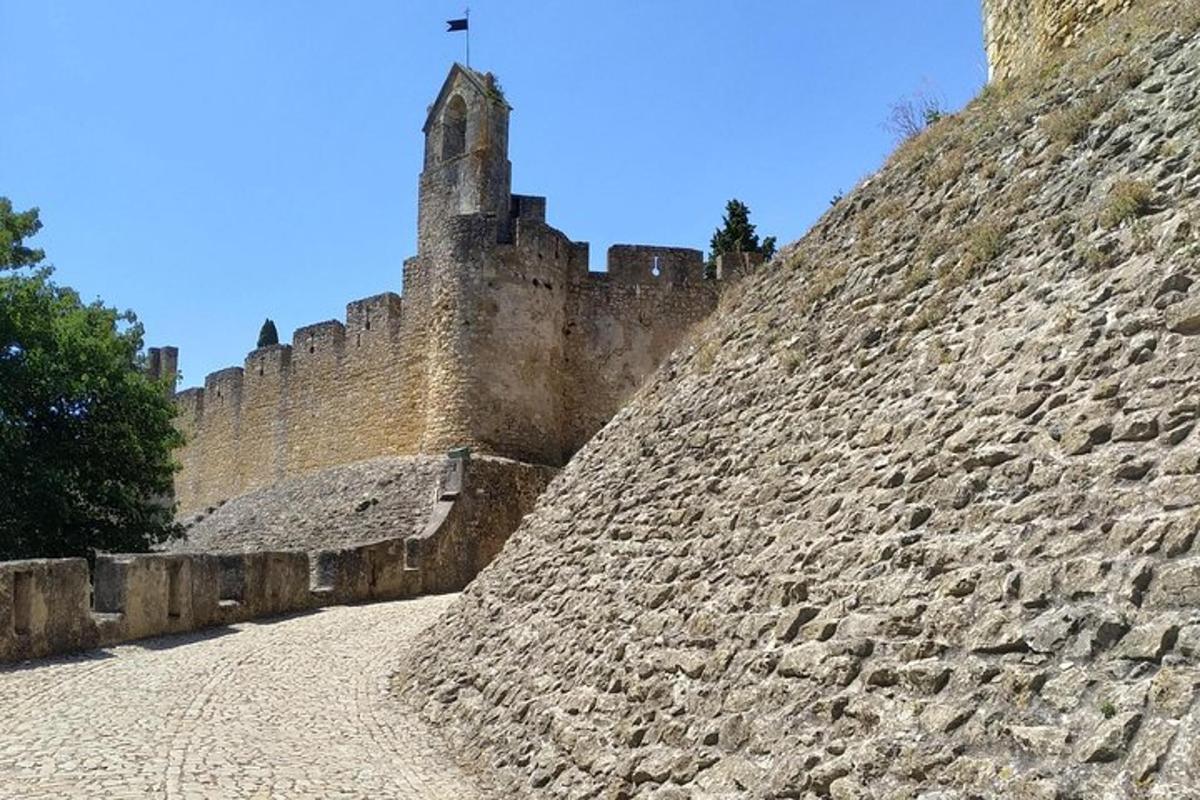 un zid de piatră cu un castel pe un deal