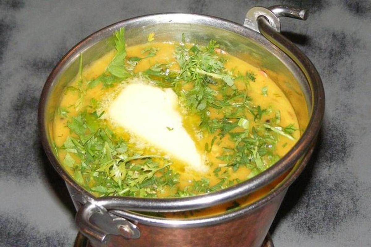 a pot of soup with cheese and greens in it