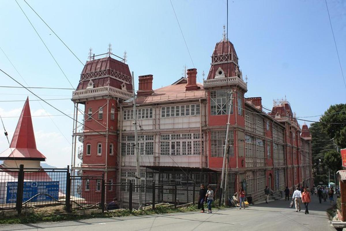 un grande edificio rosso con una torre dell'orologio su una strada