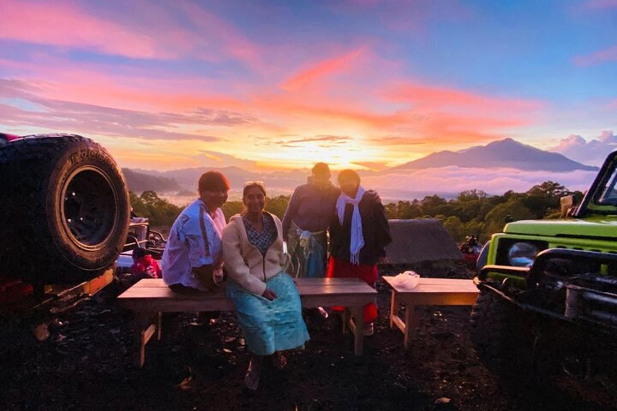 a group of people standing around a picnic table with a sunset