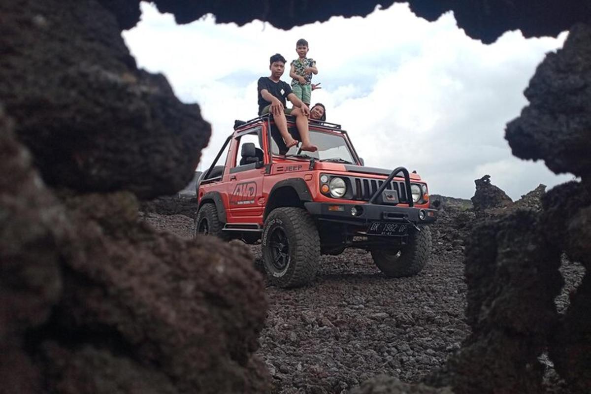 two people sitting on the top of a red jeep