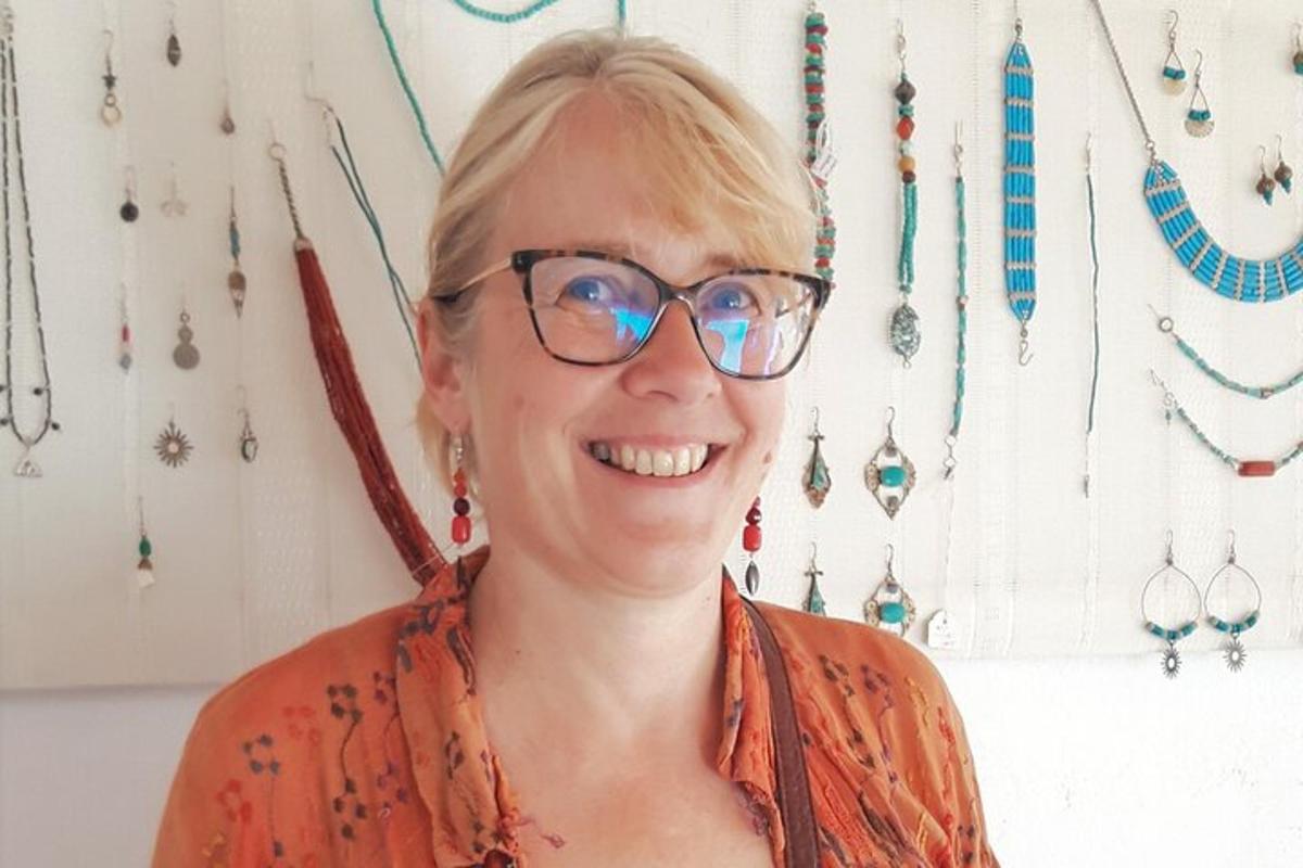 a woman wearing glasses standing in front of a wall of jewelry