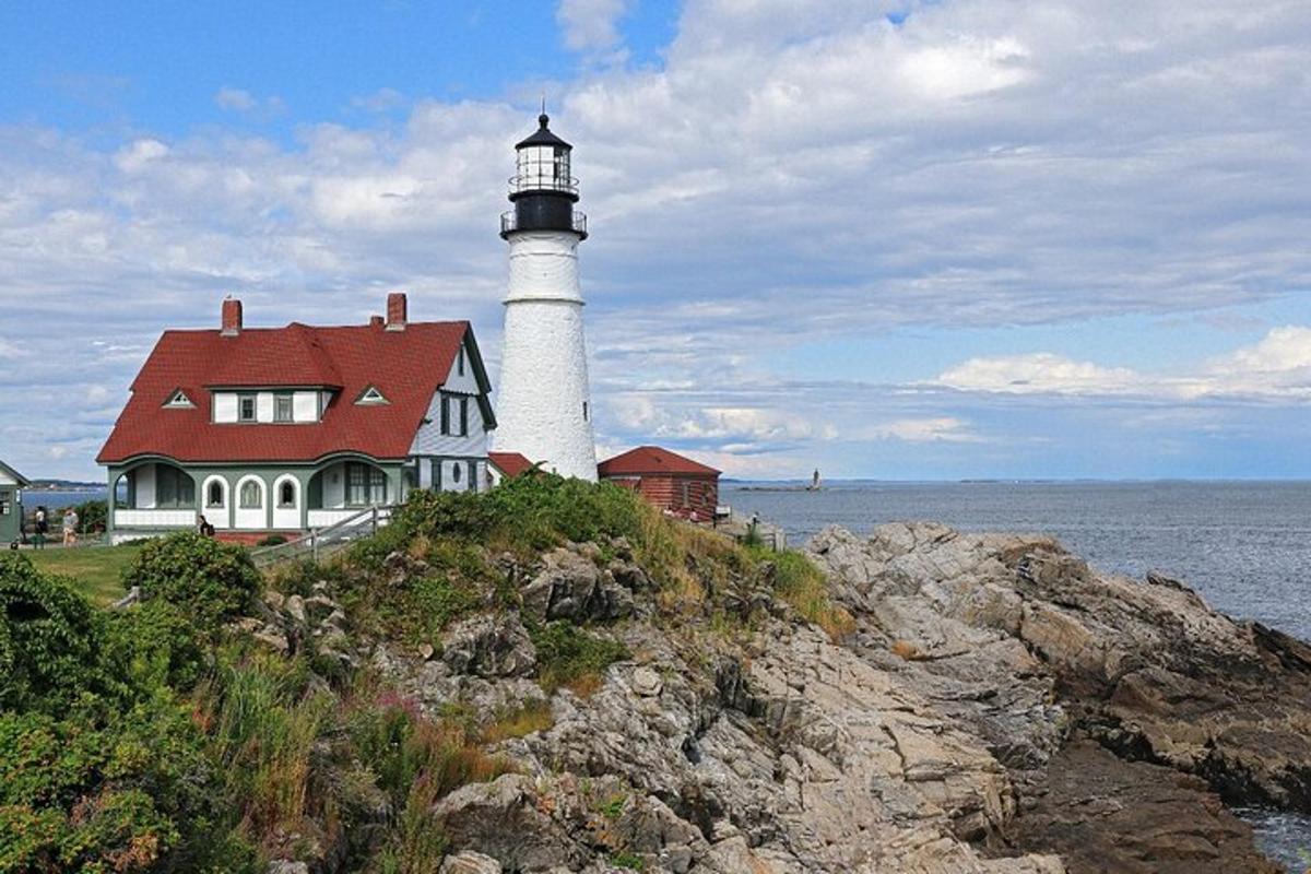 a lighthouse sitting on top of a house on a cliff