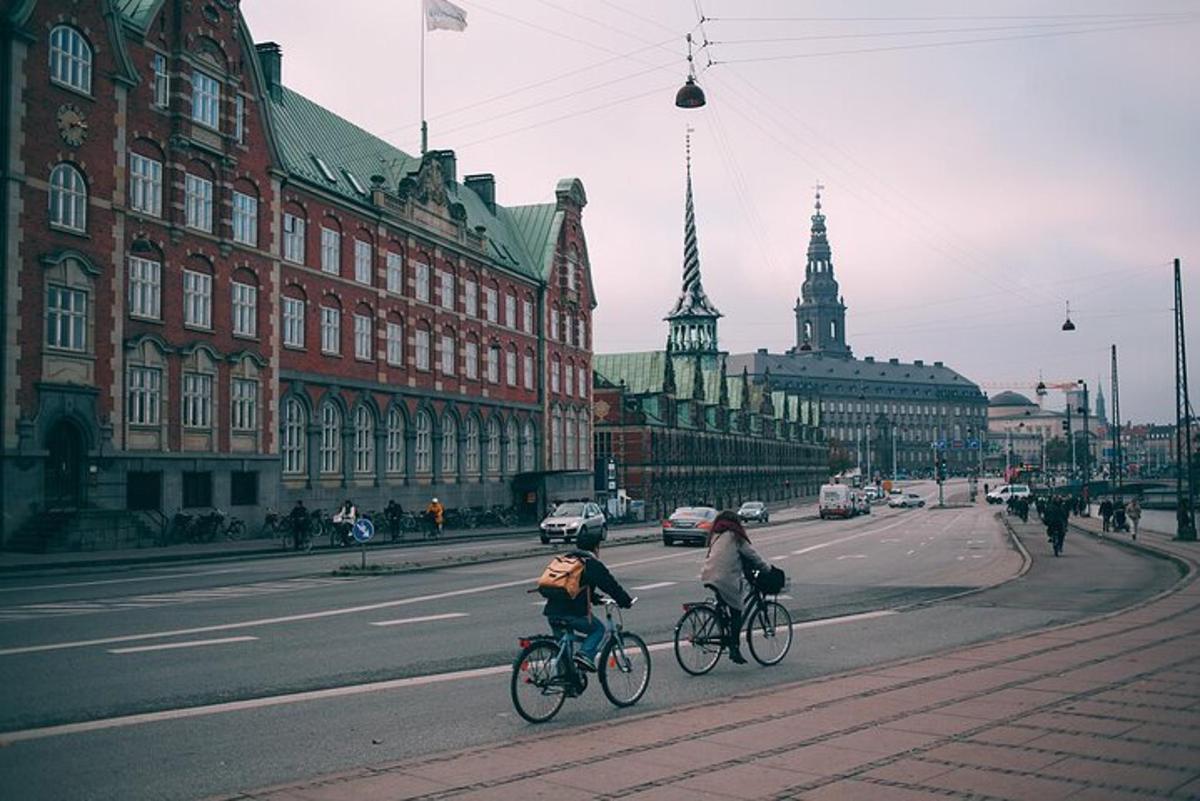 kaks inimest sõidavad jalgratastega mööda hoonetega kaetud linnatänavat
