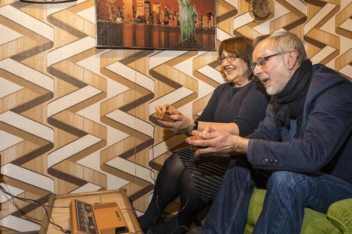 muž a žena sedící na gauči a dívající se na mobilní telefon