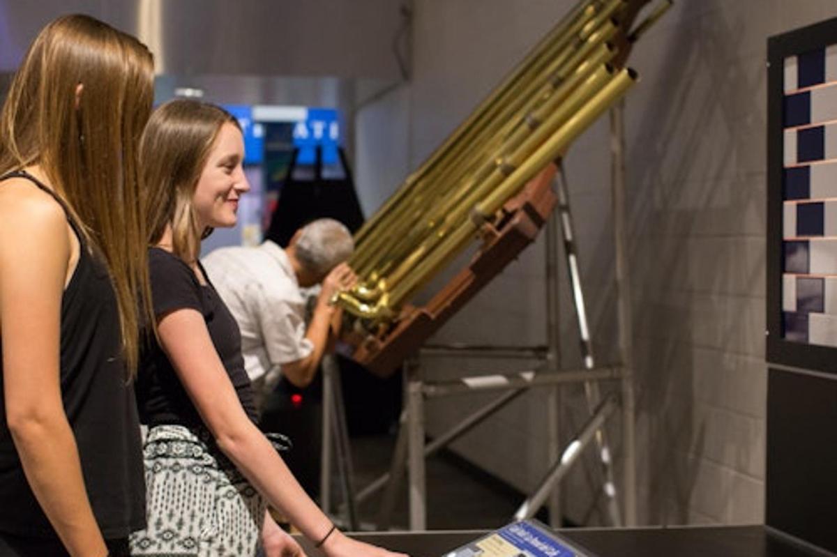 two women are standing next to a instrument