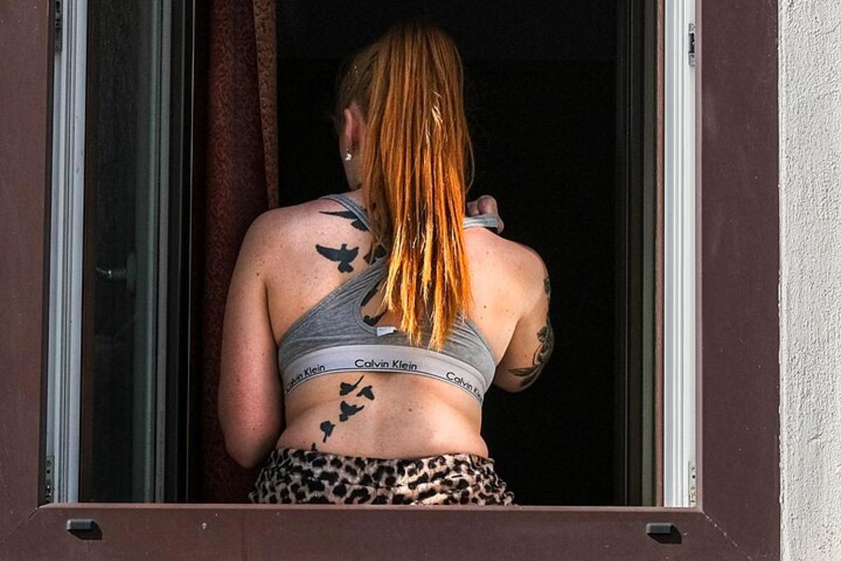 Ένας άντρας με πουλιά στην πλάτη του κοιτάζοντας έξω από ένα παράθυρο