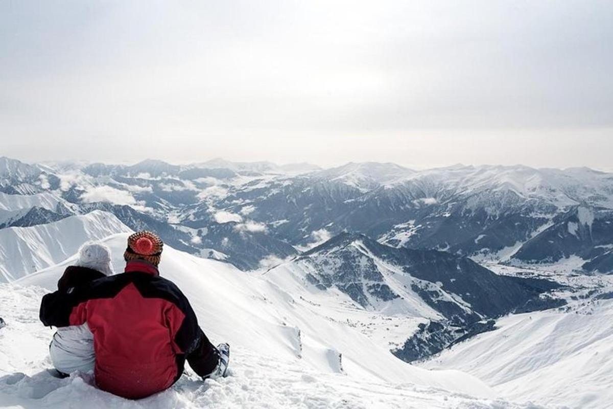 una coppia seduta in cima a una montagna innevata