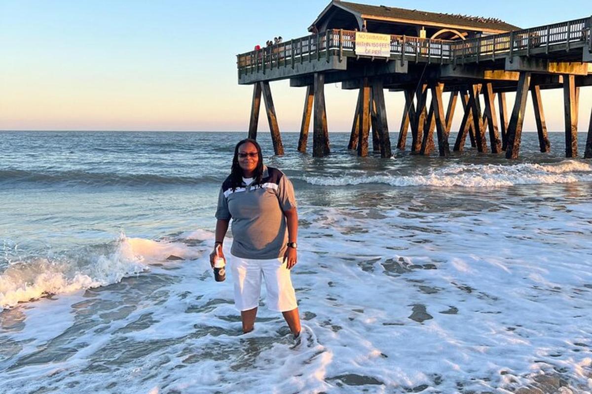 a man standing in the ocean in front of a pier