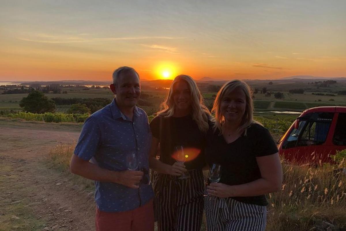 un gruppo di tre persone in piedi di fronte al tramonto