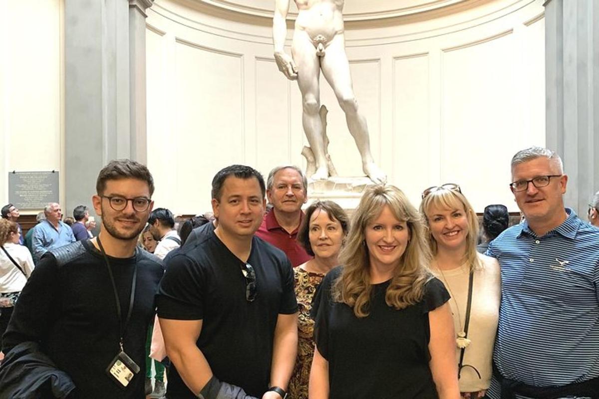 cilvēku grupa, kas stāv statujas priekšā