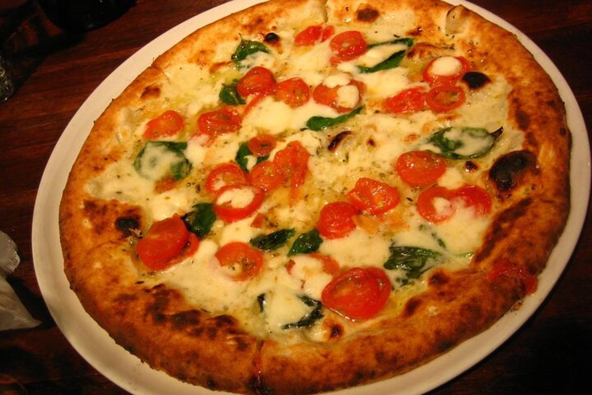 o pizza pe o farfurie albă pe o masă