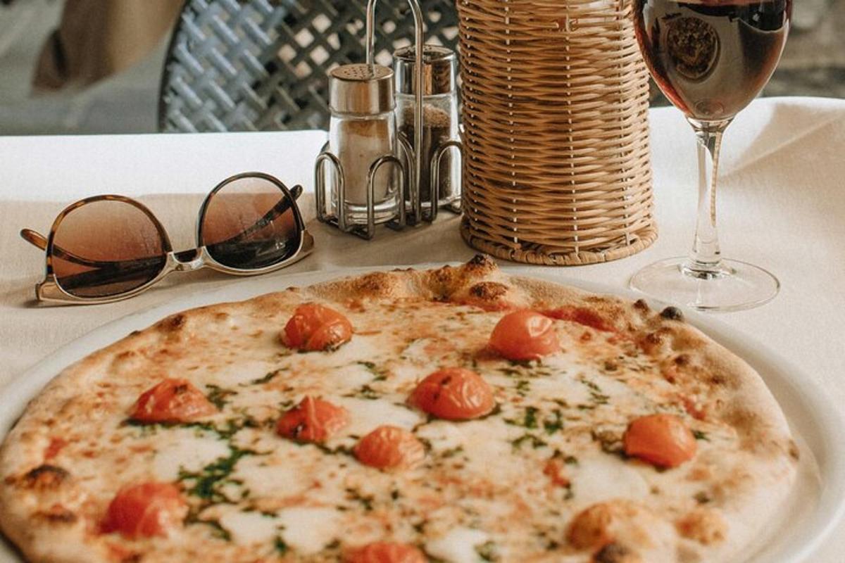 uma pizza num prato sobre uma mesa com uma taça de vinho