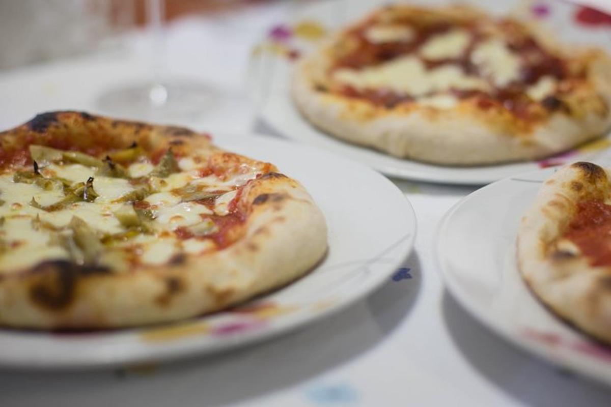 trei pizza așezate pe farfurii albe pe o masă