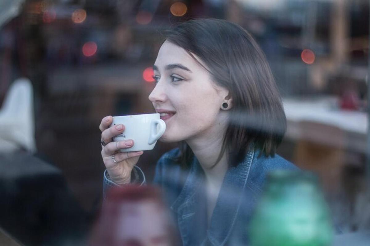 Una mujer está bebiendo de una taza de café.