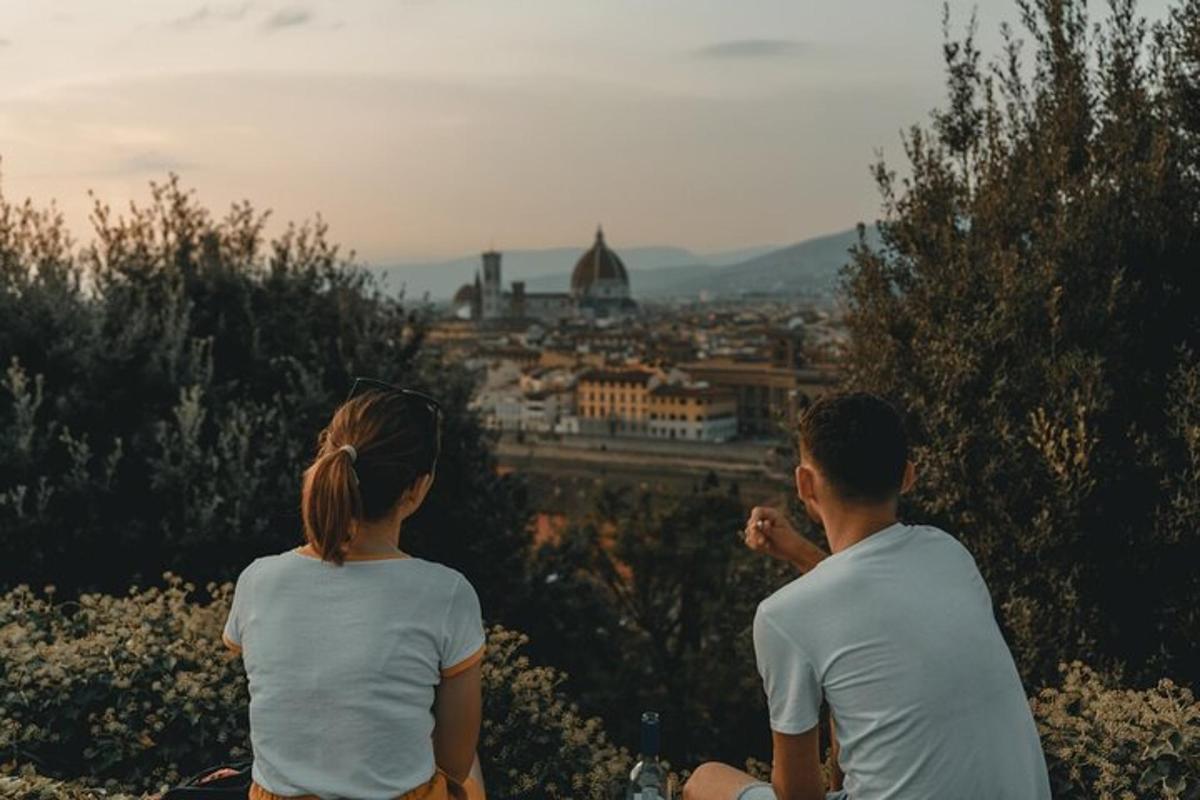 due persone sedute su una collina che guardano una città